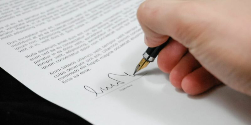 A person signs a contract with a fountain pen.