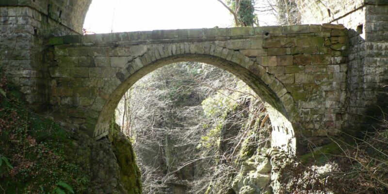 An old, arched stone bridge, known as Rumblingbridge.